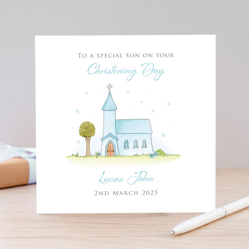 Op de afbeelding: Een vierkante wenskaart met een aquarelillustratie van een lichtblauwe kerk met een bruine deur, een groene boom en gras. De tekst luidt: TO A SPECIAL SON ON YOUR Christening Day, Lucas John, en 2ND MARCH 2025 in grijs en blauw.