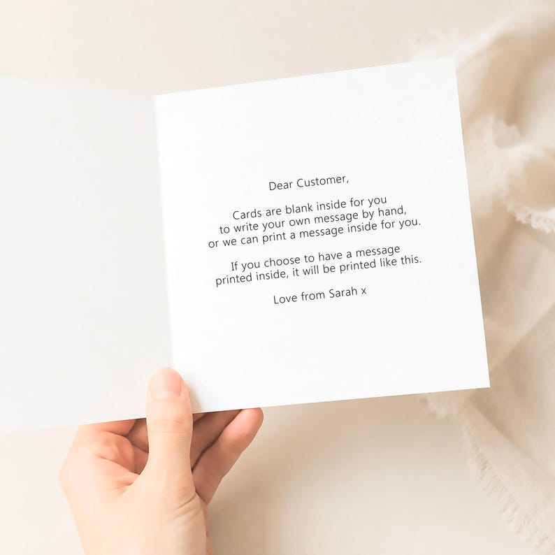 Op de afbeelding: Een witte wenskaart met zwarte tekst die luidt: Dear Customer, Cards are blank inside for you to write your own message by hand, or we can print a message inside for you. If you choose to have a message printed inside, it will be printed like this. Love from Sarah x.