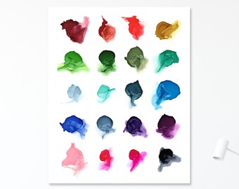 May include: A framed art print featuring a grid of colorful abstract ink blotches in shades of red, green, blue, and purple. The artwork hangs above a modern desk with a gray chair and a gray blanket.