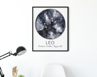 May include: A framed art print featuring the Leo zodiac sign. The artwork displays a dark, abstract watercolor background with a constellation overlay. The text "LEO" and the words "Cheerful. Creative. Passionate" are below the image. The print is displayed on a white wall.