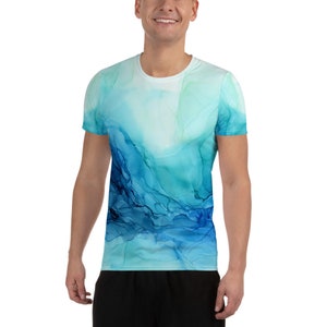 May include: A short-sleeved t-shirt with a vibrant abstract design in shades of blue and teal. The pattern resembles flowing watercolor or ink, creating a dynamic and artistic look. The shirt is made of a lightweight, breathable material.