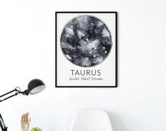May include: A framed print of the Taurus constellation in a monochrome abstract style. The print displays the word "TAURUS" and the words "Devoted. Patient. Reliable." The print hangs on a white wall above a white chair with folded jumpers.