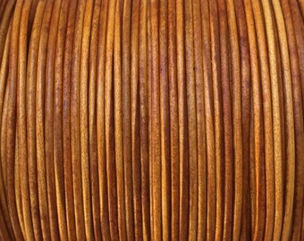 May include: Close-up of a spool of brown leather cord. The cord is tightly wound and has a smooth, polished finish.