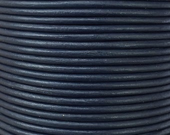 Op de afbeelding: Een close-up van een spoel donkerblauw lederen koord. Het koord is strak gewikkeld en heeft een glad, licht getextureerd oppervlak.