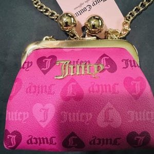 May include: A pink Juicy Couture purse with a gold chain strap and gold accents. The purse has a heart pattern with the Juicy Couture logo repeated throughout.