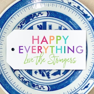 May include: A white gift tag with the text "HAPPY EVERYTHING Love the Stringers" in rainbow colors on a blue and white patterned plate.