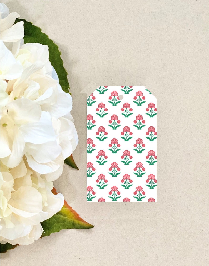 K&ouml;nnte beinhalten: Wei&szlig;er Geschenkanh&auml;nger mit einem sich wiederholenden Muster aus rosa Bl&uuml;ten und gr&uuml;nen Bl&auml;ttern.