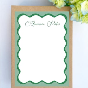 May include: A brown card with a green border and a scalloped edge. The card has the text "Genevieve Porter" written in cursive.