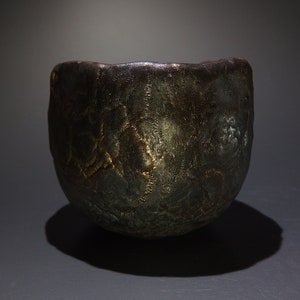 May include: A dark brown ceramic bowl with a textured surface. The bowl has a slightly irregular shape and a wide rim.
