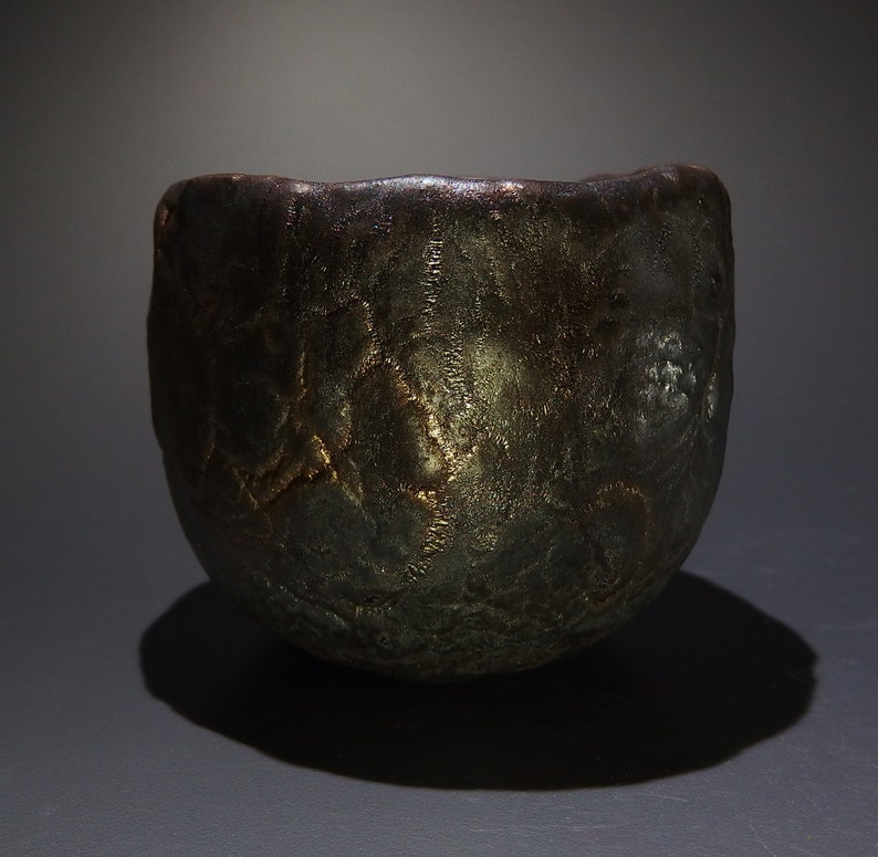 May include: A dark brown ceramic bowl with a textured surface. The bowl has a slightly irregular shape and a wide rim.