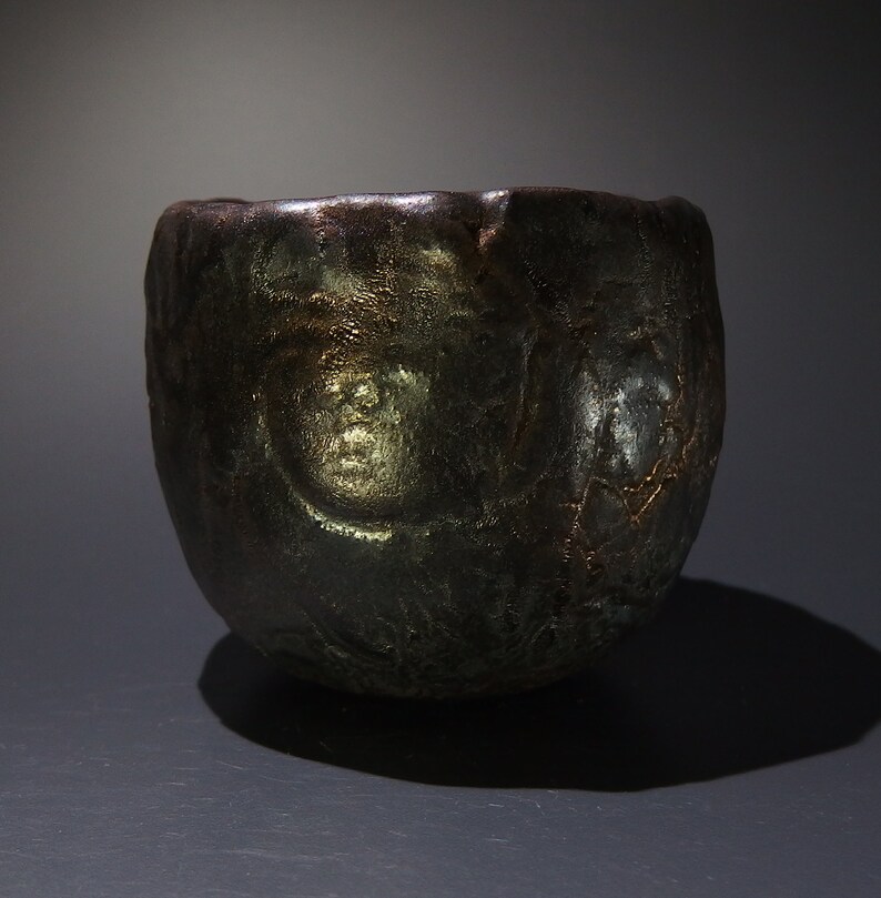 May include: A dark gray ceramic bowl with a textured surface and a metallic sheen. The bowl has a rounded shape and a wide opening.