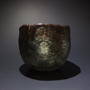 May include: A dark brown ceramic teacup with a textured surface and a metallic sheen.