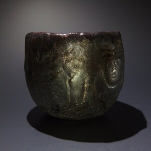 May include: A dark gray ceramic bowl with a textured surface. The bowl has a rounded shape and a wide rim.