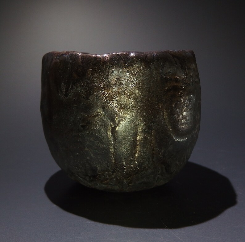 May include: A dark gray ceramic bowl with a textured surface. The bowl has a rounded shape and a wide rim.