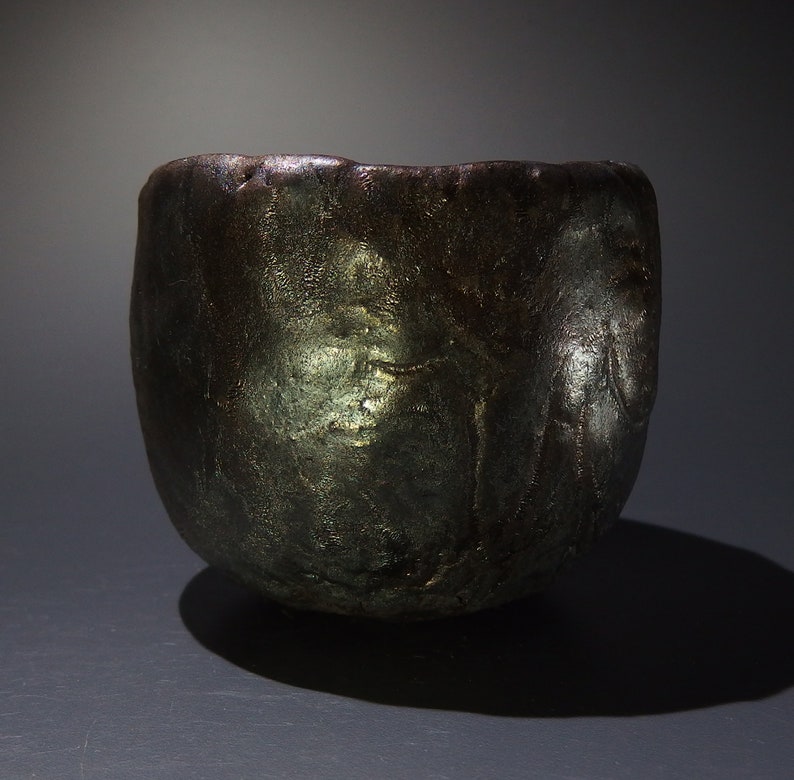 May include: A dark gray ceramic bowl with a textured surface. The bowl has a wide rim and a rounded bottom.