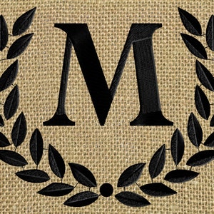 May include: A black letter M surrounded by a black wreath of leaves on a burlap background.