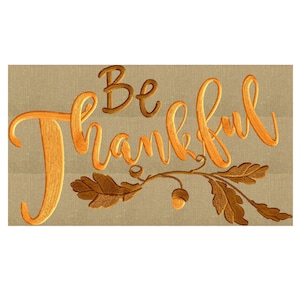 Pode incluir: Design bordado com o texto "Be Thankful" em laranja e marrom sobre um fundo bege. O design inclui um galho com folhas e bolotas.