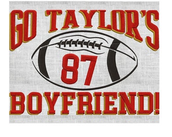 May include: Embroidered design on a light gray background. The text "GO TAYLOR'S BOYFRIEND!" is in red with gold trim. A black and white football graphic features the number 87 in red.