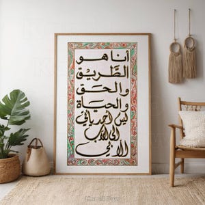 Könnte beinhalten: Ein gerahmter Druck mit weißem Hintergrund und schwarzer arabischer Kalligraphie. Die Kalligraphie ist von einem bunten Rahmen mit floralen Mustern umgeben. Der Text lautet "أنا هو القادر والحفيظ والحيّ الذي لا يموت الله"
