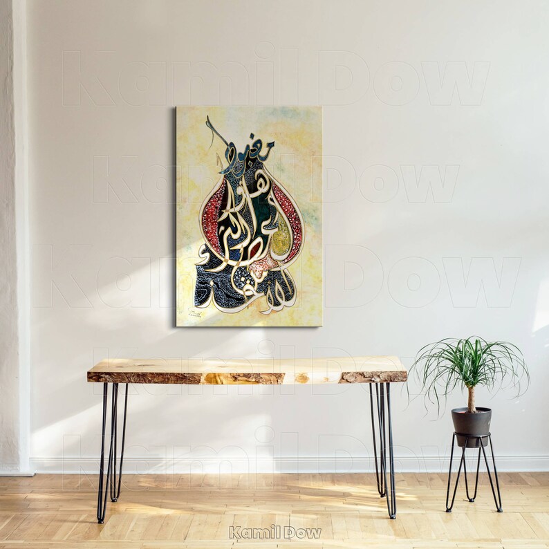 Pu&ograve; includere: Un dipinto di calligrafia araba in nero, oro e rosso su uno sfondo crema. La calligrafia &egrave; in stile decorativo ed &egrave; incorniciata in una cornice nera semplice. Il dipinto &egrave; appeso a una parete bianca sopra un tavolo di legno con gambe a forcina nere.