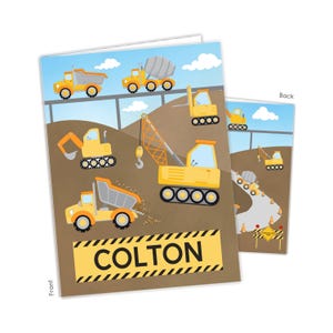 May include: A rectangular greeting card featuring a construction theme with yellow dump trucks, a crane, and a cement mixer on a brown dirt background under a blue sky. The front displays the name COLTON in black letters on a yellow caution stripe.