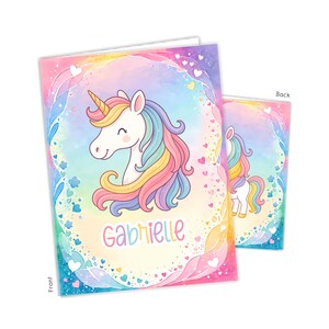 May include: A greeting card featuring a watercolor illustration of a unicorn with a rainbow mane and horn. The card has a pastel color scheme with the name "Gabrielle" written in pink script. The back of the card shows a smaller unicorn illustration.