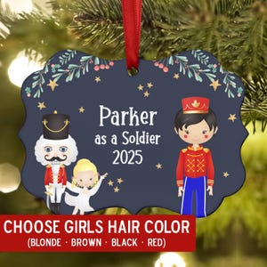 May include: Navy blue ornament with a red ribbon, featuring a soldier and ballerina design. The text reads "Parker as a Soldier 2025." A red banner at the bottom says "CHOOSE GIRLS HAIR COLOR (BLONDE • BROWN • BLACK • RED)."
