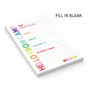 May include: A white notepad with the text HELLO FROM CAMP printed vertically in rainbow colors. The page features fill-in-the-blank lines with prompts including DEAR, HOW ARE YOU? I AM, CAMP IS, TODAY WE, I CAN'T WAIT TO, MY FAVORITE THING IS, and the name MORGAN.