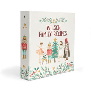 May include: A white three-ring binder featuring the text Wilson Family Recipes in red. The cover displays a watercolor illustration of a Christmas tree, a ballerina, a mouse, a nutcracker, and a figure in a top hat, accented with holly and stars.