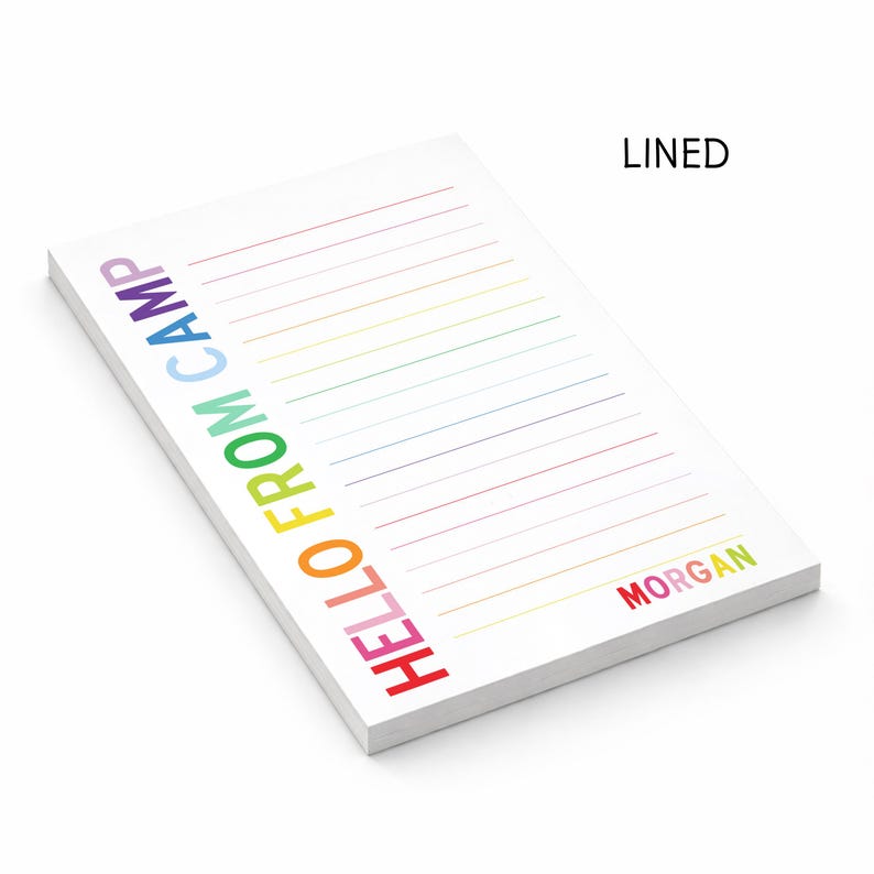 May include: A white rectangular notepad with horizontal lines. The text HELLO FROM CAMP is printed vertically in rainbow colors on the left side. The name MORGAN is printed in rainbow colors at the bottom right. The word LINED appears at the top right.