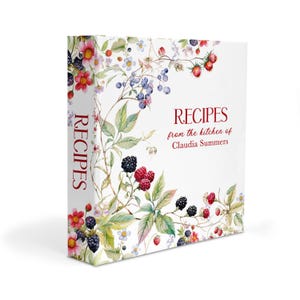 May include: A white three-ring binder featuring a watercolor illustration of blackberries, raspberries, and small flowers. The text on the front and spine reads RECIPES from the kitchen of Claudia Summers in a dark red serif and script font.