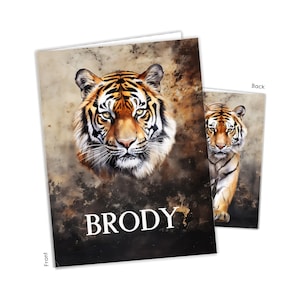 May include: A rectangular greeting card featuring a detailed illustration of a tiger's face on the front with the name BRODY printed in white capital letters below. The background has a dark, mottled texture. The back shows a full-body tiger.