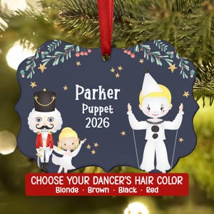 May include: A dark blue scalloped Christmas ornament with a red ribbon, featuring a nutcracker, a blonde dancer, and a white-clad puppet. The text reads Parker, Puppet, 2026, and Choose Your Dancer's Hair Color: Blonde, Brown, Black, Red.