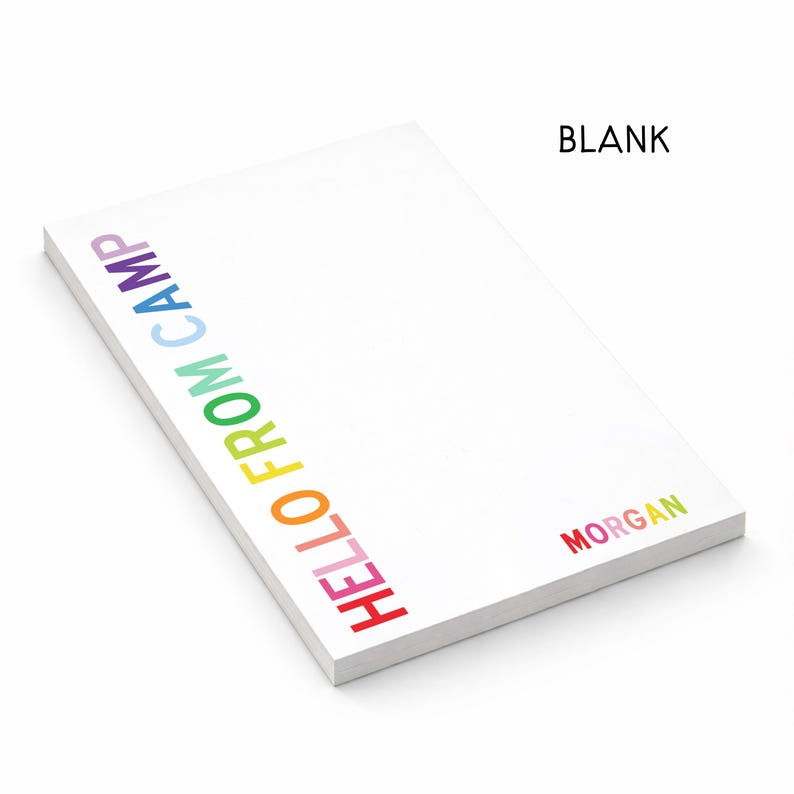 May include: A white rectangular notepad featuring the text HELLO FROM CAMP printed vertically in a rainbow gradient along the left side and the name MORGAN printed in rainbow colors in the bottom right corner, with the word BLANK at the top right.