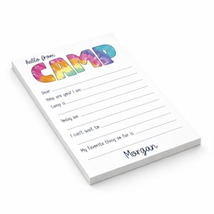 May include: White notepad with the words "hello from CAMP" in tie-dye lettering. The notepad has lines for writing and the name "Morgan" at the bottom. Ideal for camp letters.