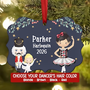May include: A dark blue, scalloped-edge holiday ornament featuring a nutcracker, a small blonde dancer, and a larger dancer in a black and white harlequin-patterned tutu. The text reads Parker, Harlequin, 2026, and Choose Your Dancer's Hair Color.
