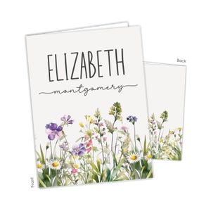 May include: A white card with a floral design. The card has the text "ELIZABETH montgomery" on the front.