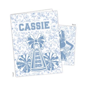 May include: A greeting card featuring a light blue floral pattern. The front displays the name CASSIE in block letters above a cheer megaphone with a bow and two pom-poms. The back shows a silhouette of a cheerleader holding a pom-pom.