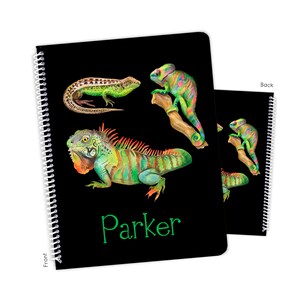 May include: Black spiral notebook with a green, red, and yellow iguana, a green lizard, and a green and pink chameleon. The notebook has the name "Parker" written in green on the front.