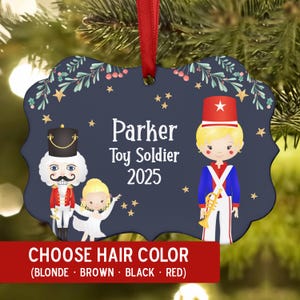 May include: Navy blue Christmas ornament with a red ribbon. The ornament features a toy soldier theme with the name "Parker" and the year "2025". The bottom of the ornament has a red banner that says "CHOOSE HAIR COLOR".