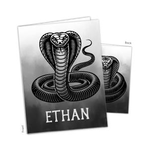 May include: Two cards with a black and white illustration of a cobra snake. The snake is coiled with its hood flared, and the name "ETHAN" is printed in white block letters. The background has a gradient effect.