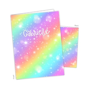 May include: A rainbow-colored notebook with a sparkly background and the name "Gabrielle" written in white on the front cover. The back cover has the same sparkly rainbow background.