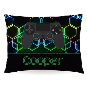 May include: Black and green pillow with a neon green geometric pattern and a black video game controller in the center. The name "Cooper" is printed in green at the bottom.