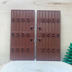 May include: Two brown wooden doors with hinges and metal accents. The doors are made of plastic and are designed to be used with Lego building blocks.