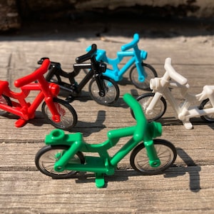 Puede incluir: Cuatro bicicletas de juguete en diferentes colores: rojo, negro, azul y blanco. Las bicicletas son de plástico y tienen ruedas con radios.