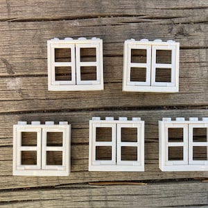 May include: Five white plastic double-pane windows with a Lego-style design. Each window has two panes and a white frame.