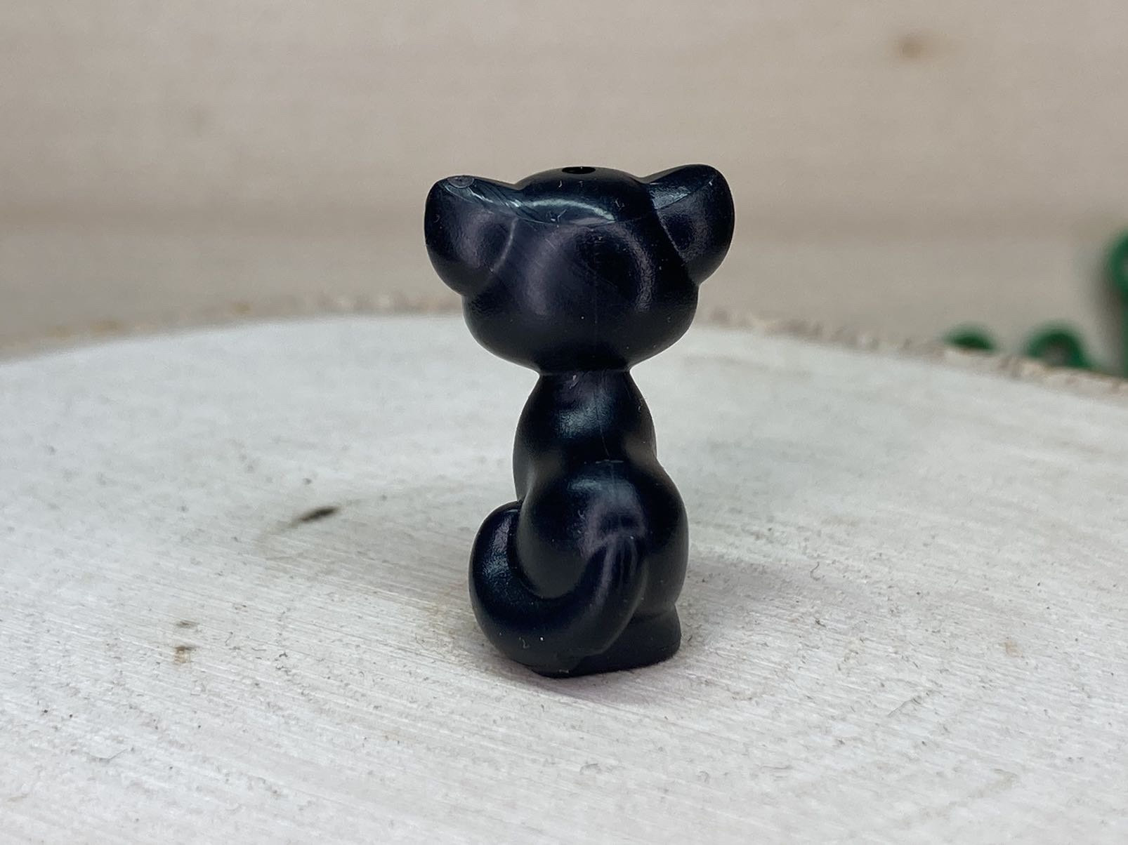 濃いピンクの耳、鼻、舌、白い顔、緑の目をした黒猫（ルシファー