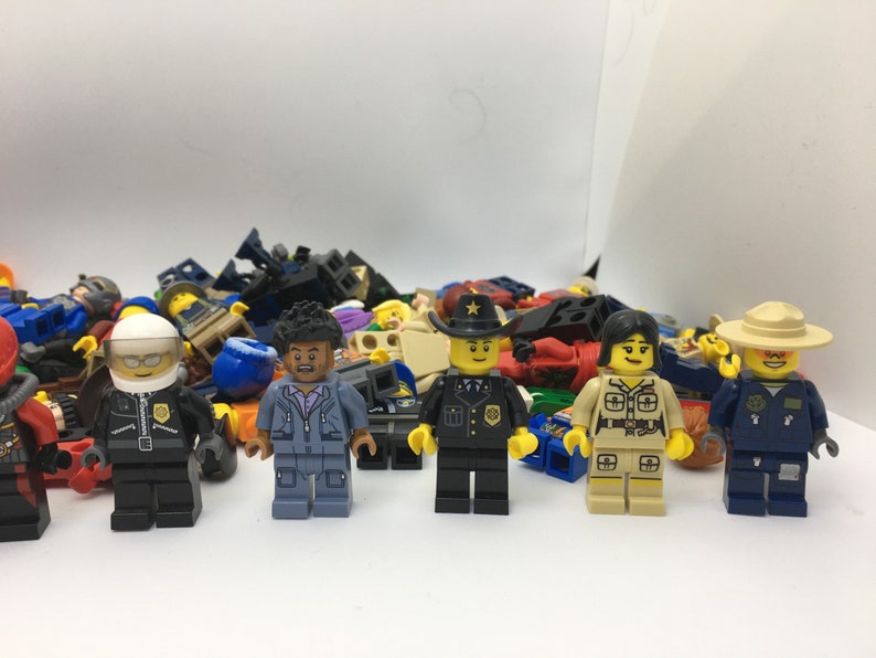 May include: A collection of colorful Lego minifigures, including a police officer, a park ranger, a construction worker, and a pilot. The minifigures are all standing on a white surface.