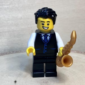 Saxofonista con chaleco negro y corbata azul y negra sosteniendo