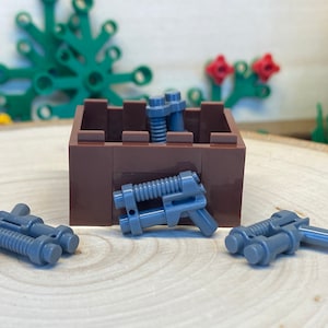 May include: Four grey plastic toy guns in a brown wooden box. The guns have a futuristic design with a barrel and a handle.